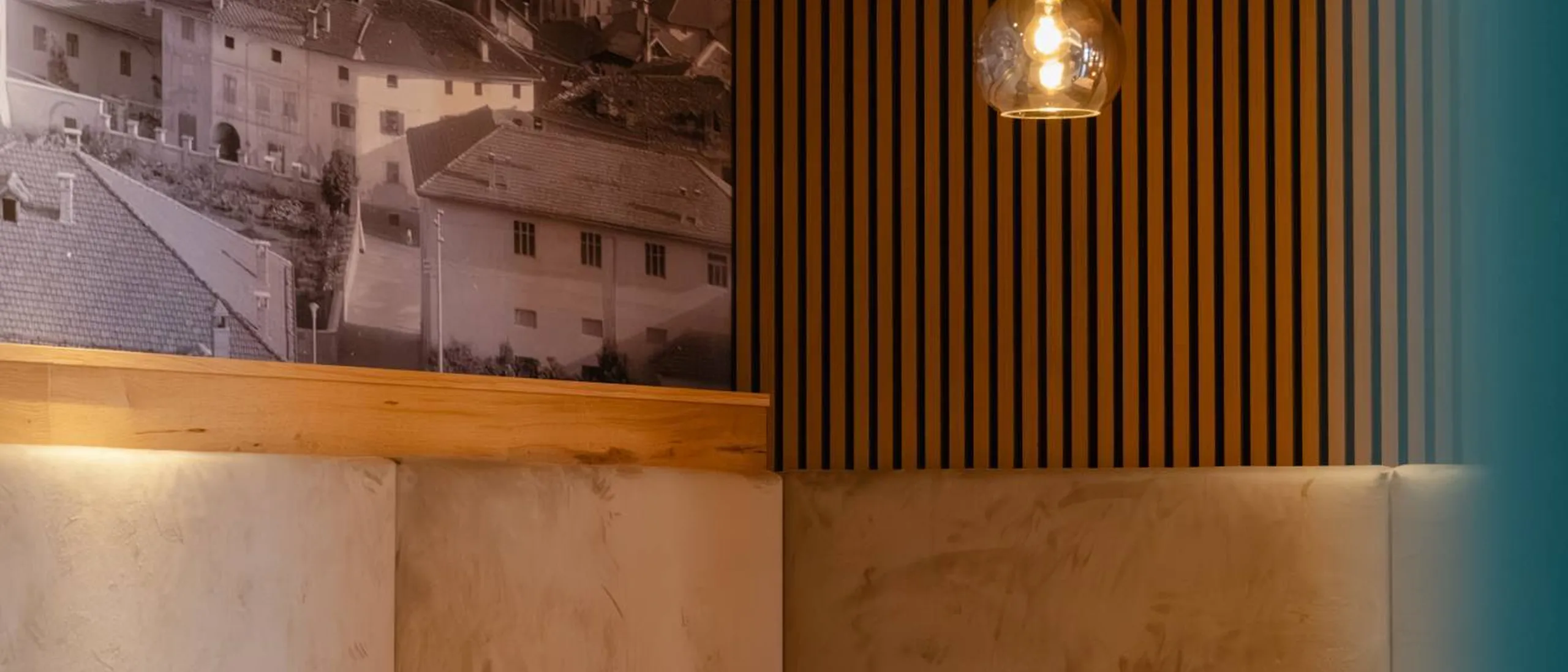 Interni moderni di ristorante: tavoli con tovaglie bianche, sedie azzurre, lampade a bulbo, pareti in legno a strisce e murale urbano in bianco e nero.