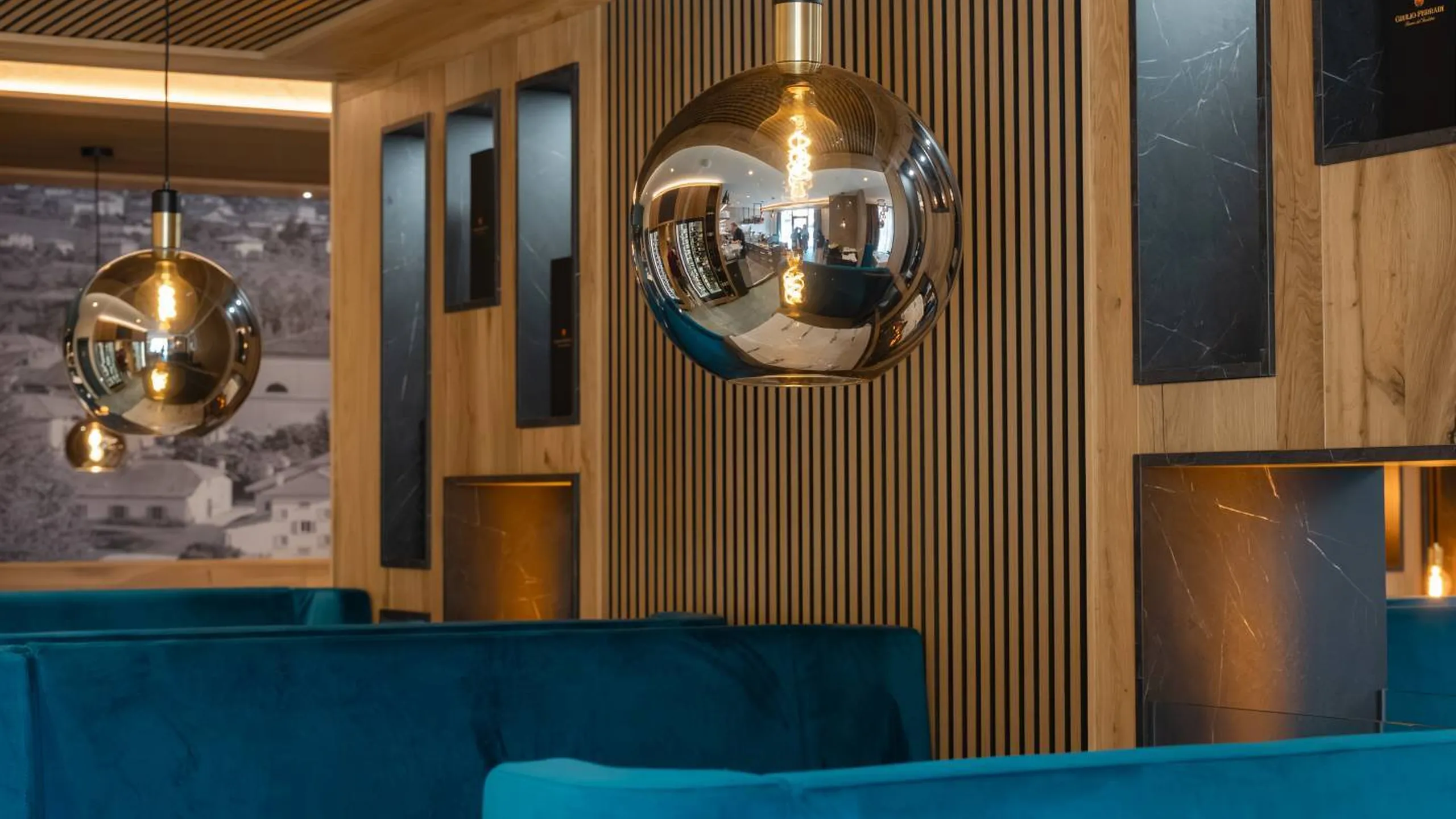 Interno ristorante Silenzia: panche blu in velluto, pareti in legno a listelli, lampadari cromati riflettenti; atmosfera calda e moderna.