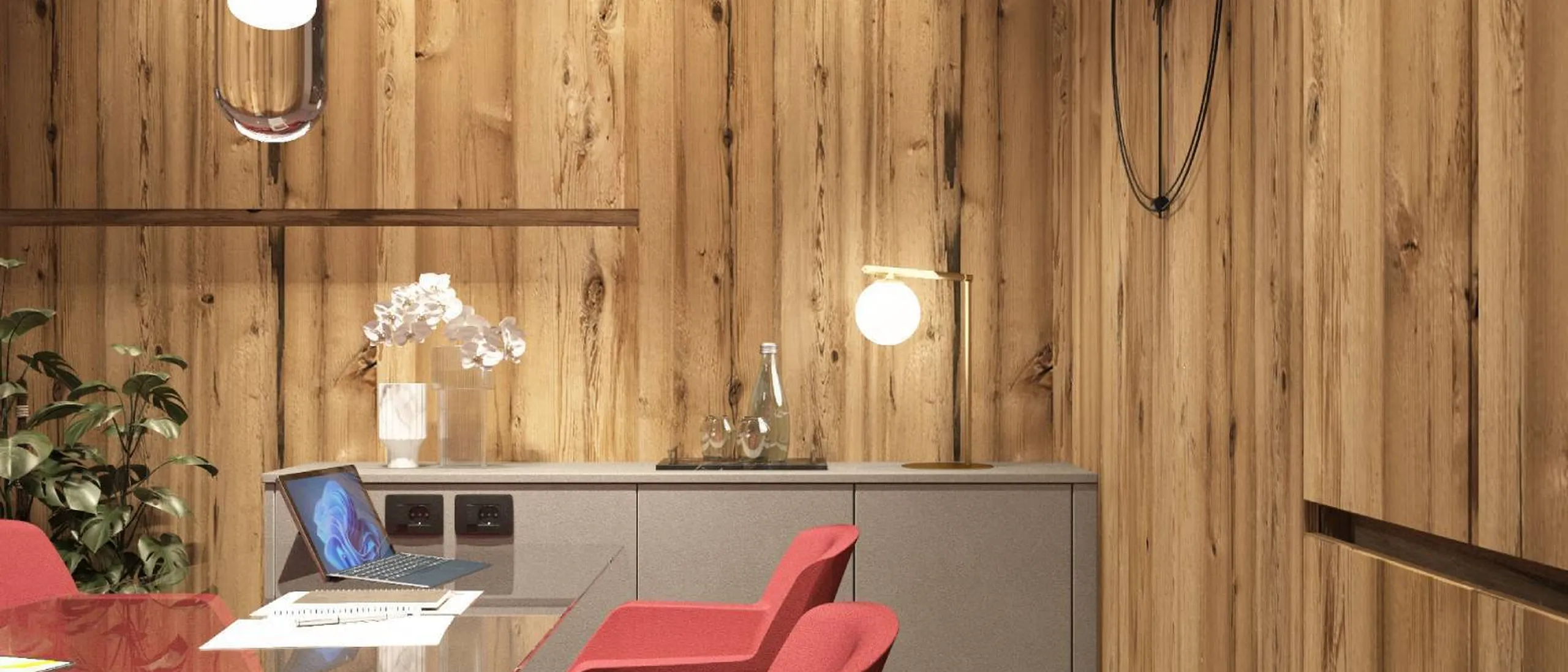 Sala riunioni con pareti in legno, tavolo in vetro, sedie rosse, lampade e una console grigia; soffitto rosso a onde.